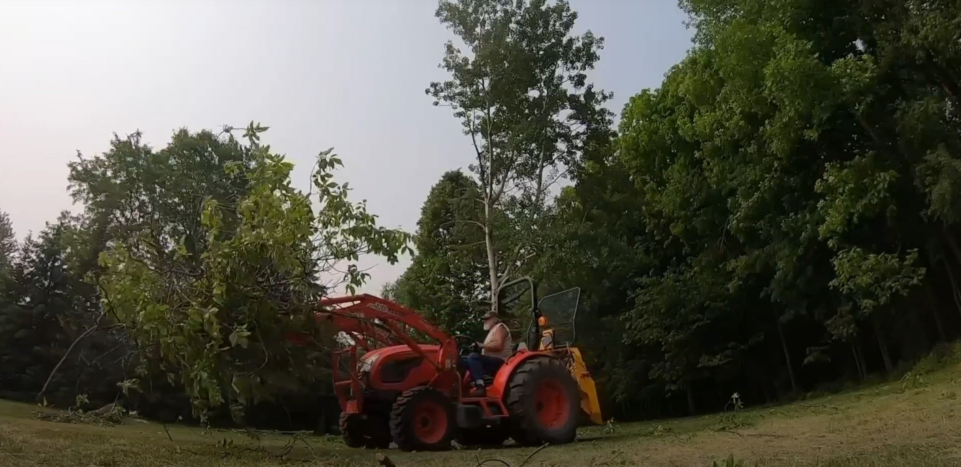 Large specialized tree removal equipment working on residential property with red tractor and professional crew