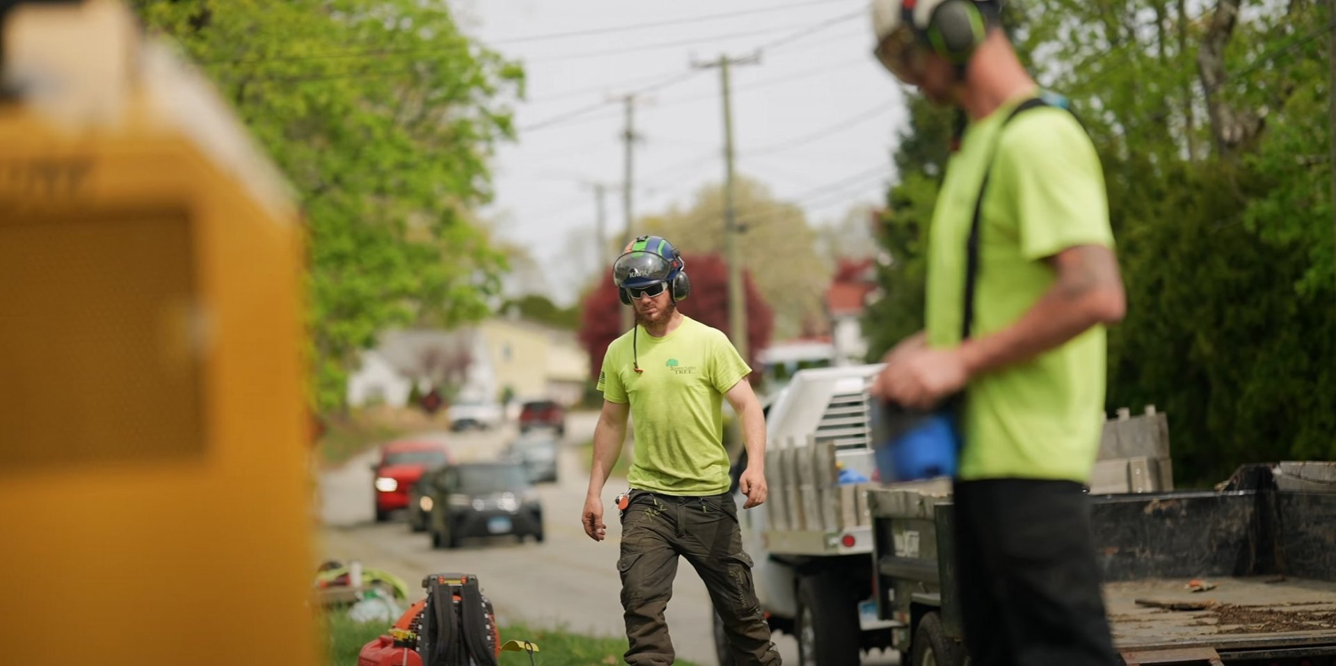 Tree service professionals in safety gear working on street with specialized equipment and vehicles