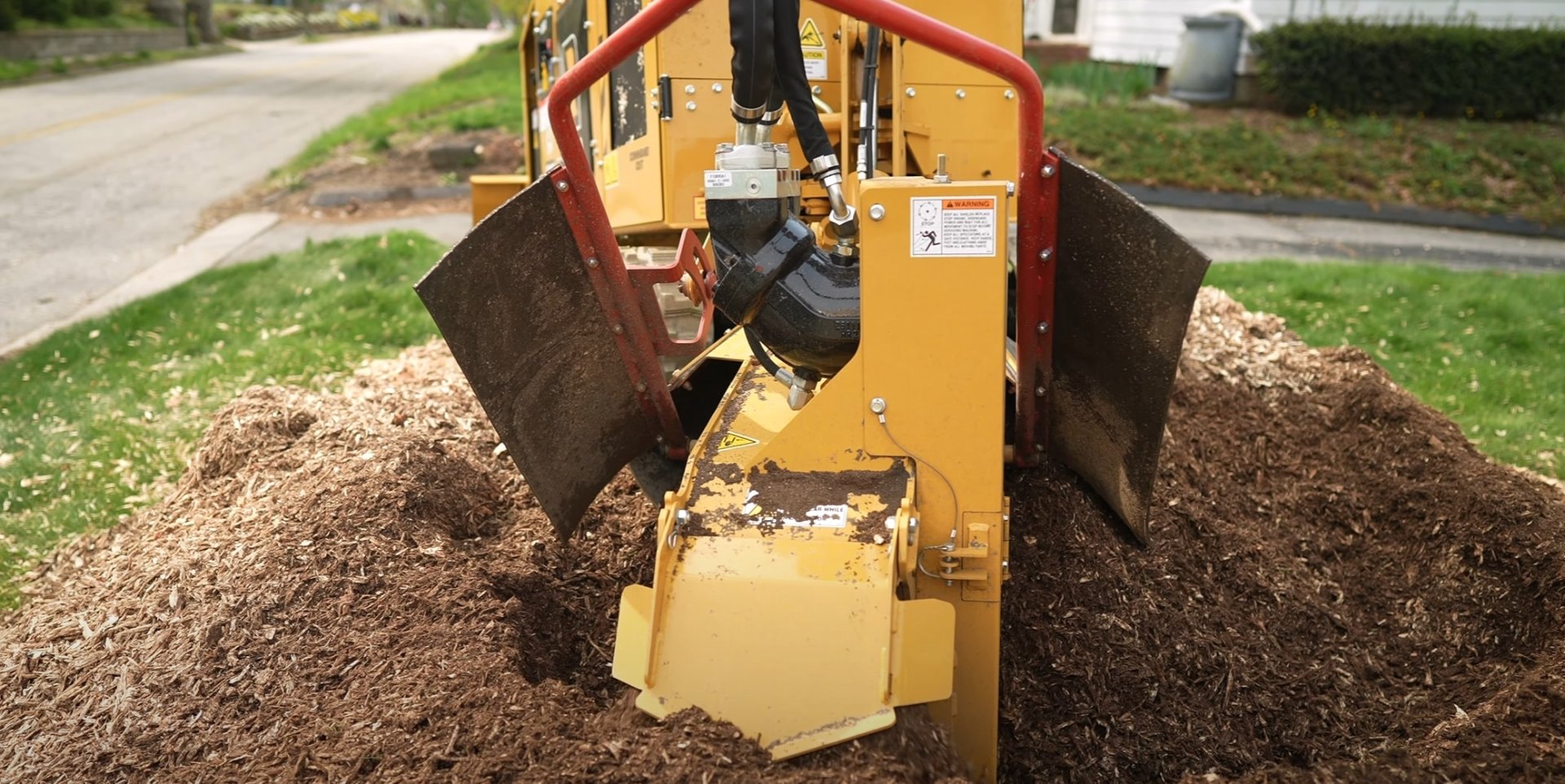 Heavy-duty stump grinding equipment removing tree stump with wood chips scattered around